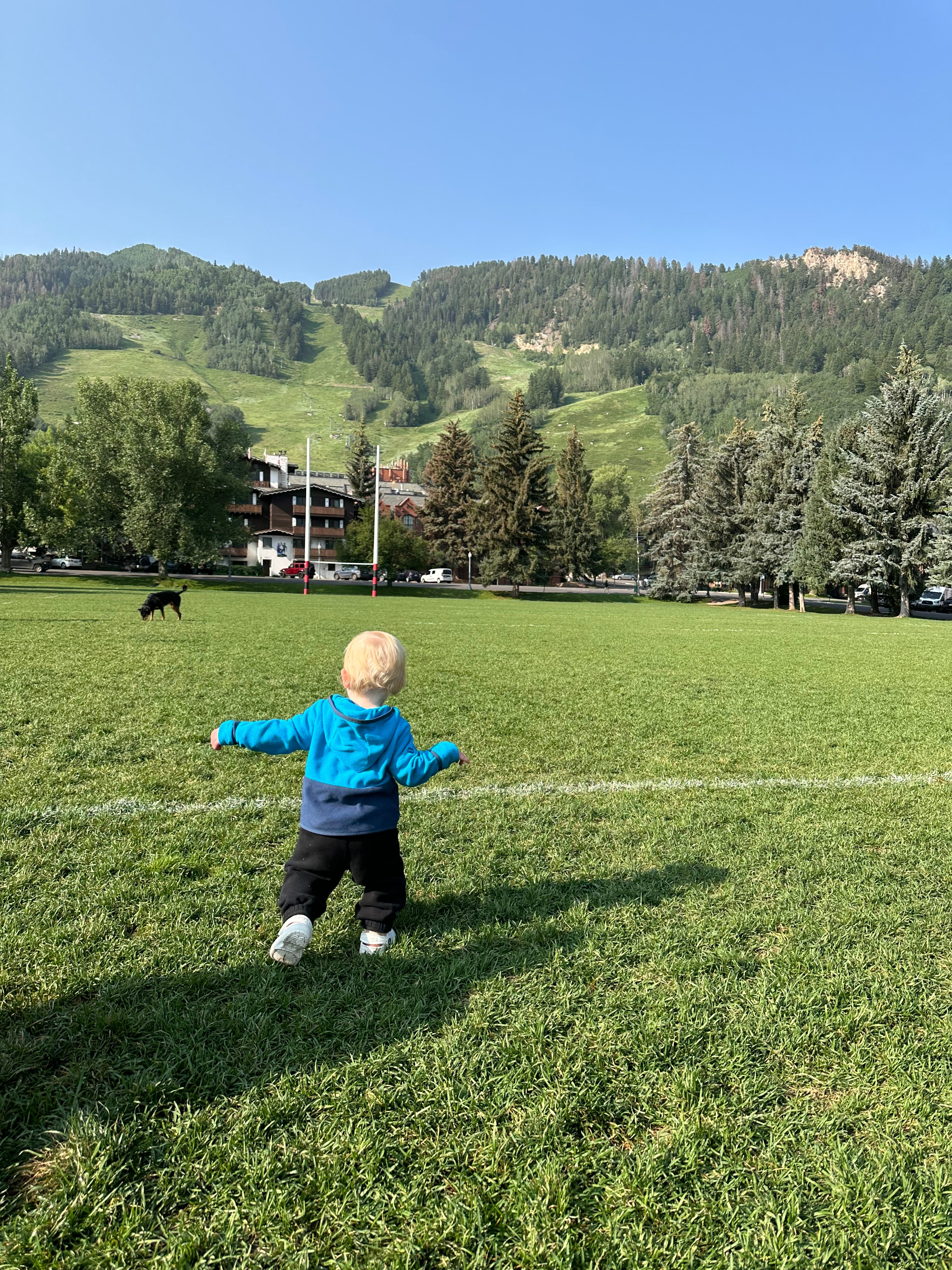 Toddler running on rugby field at the base of mountains