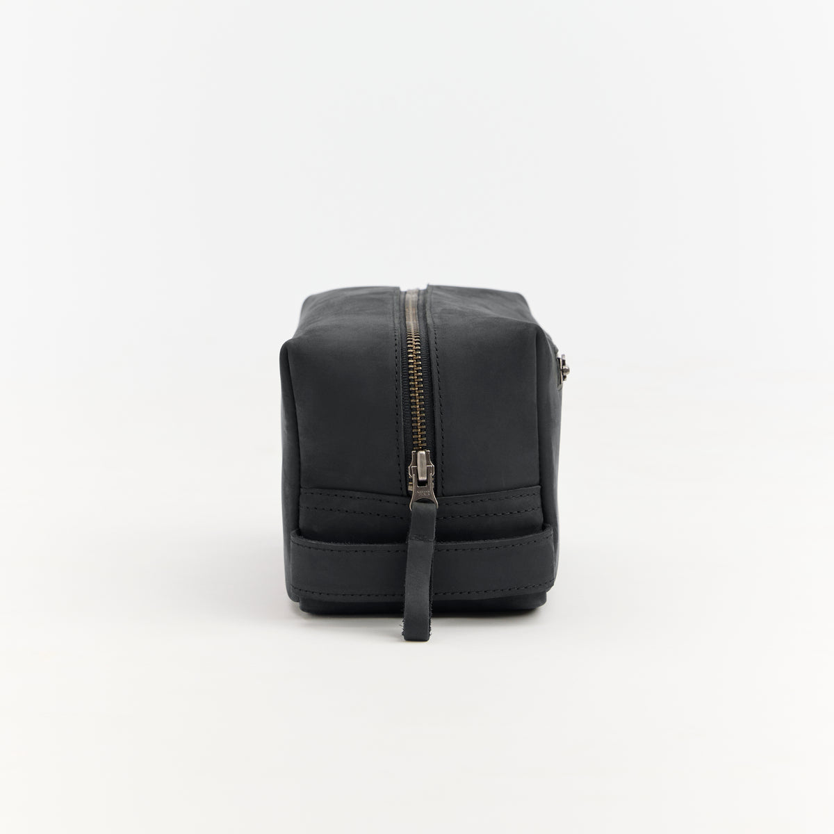Black leather toiletry bag with a zipper on a white background