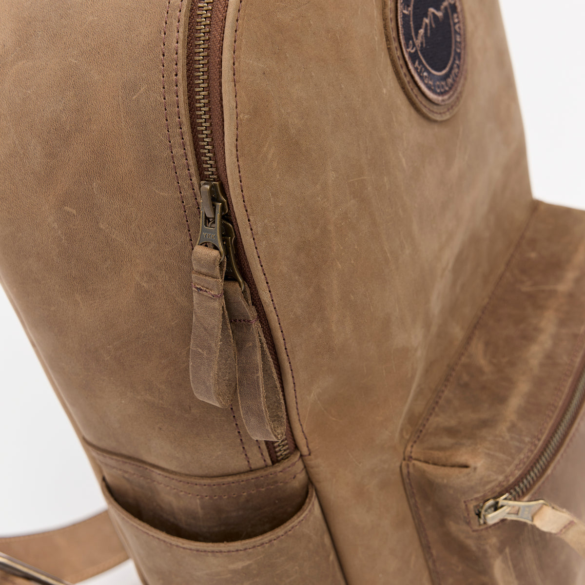 Close-up of a brown leather backpack with a zipper and the Everwest brand logo.