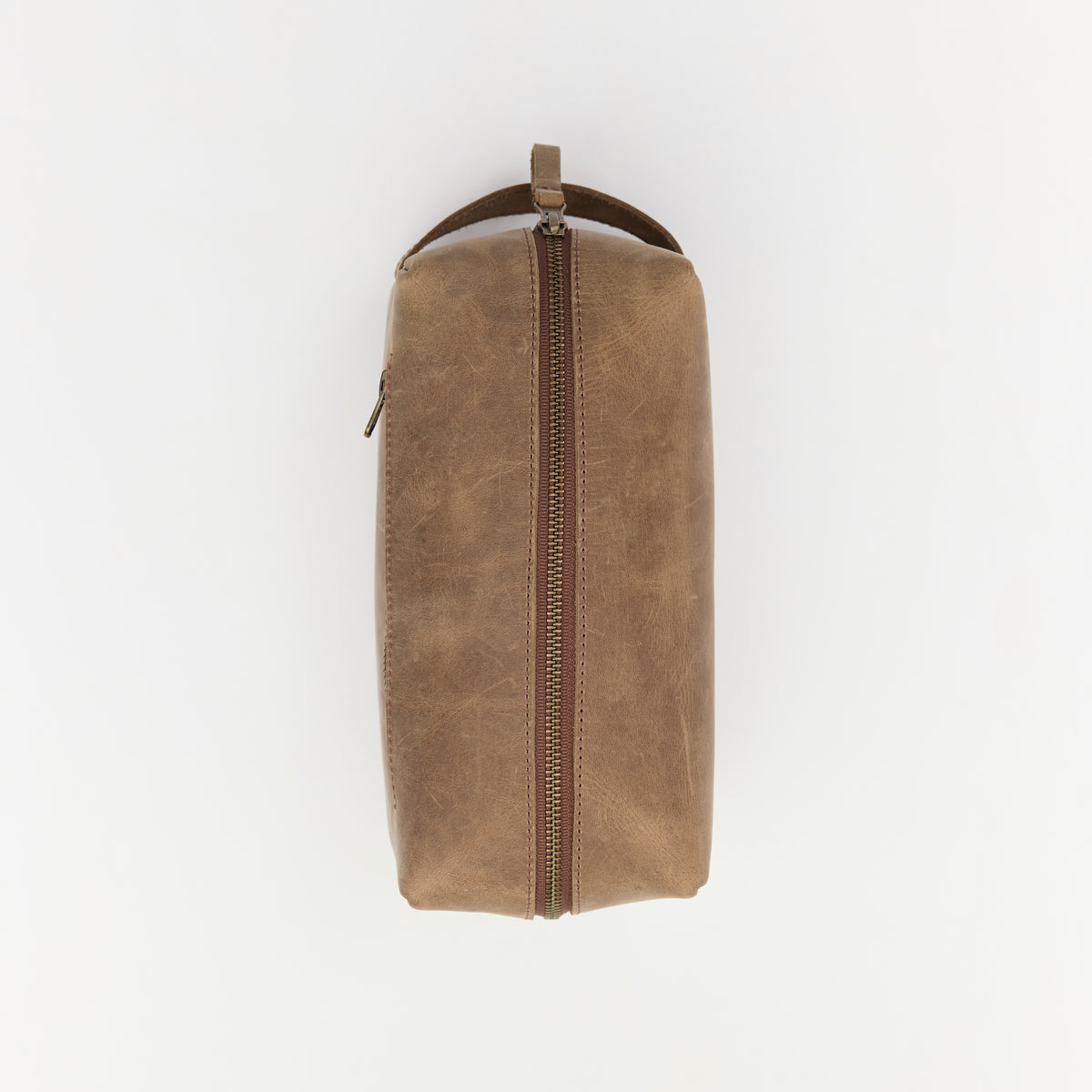 Brown leather toiletry bag with a zipper on a white background