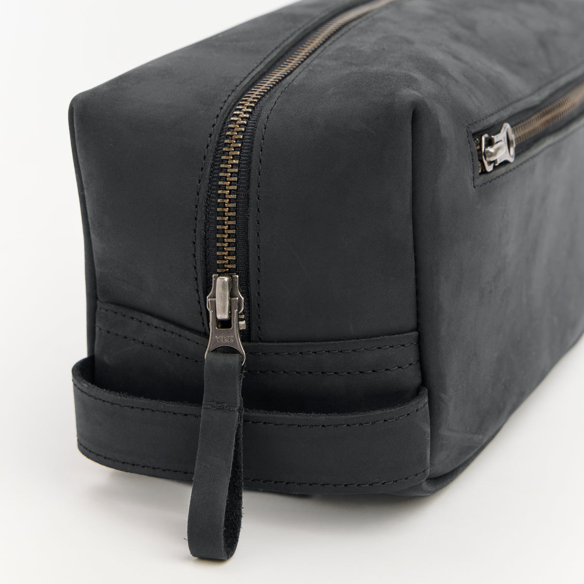 Black leather dopp kit with zipper on a white background