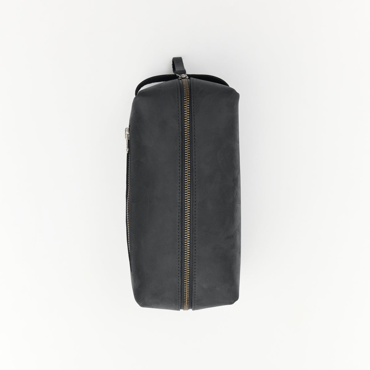 Black leather dopp kit with antique nickel zipper on a white background