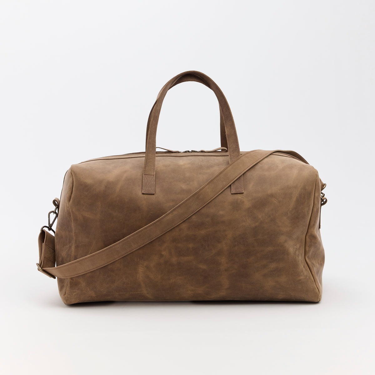 Brown leather duffel bag with a shoulder strap on a white background