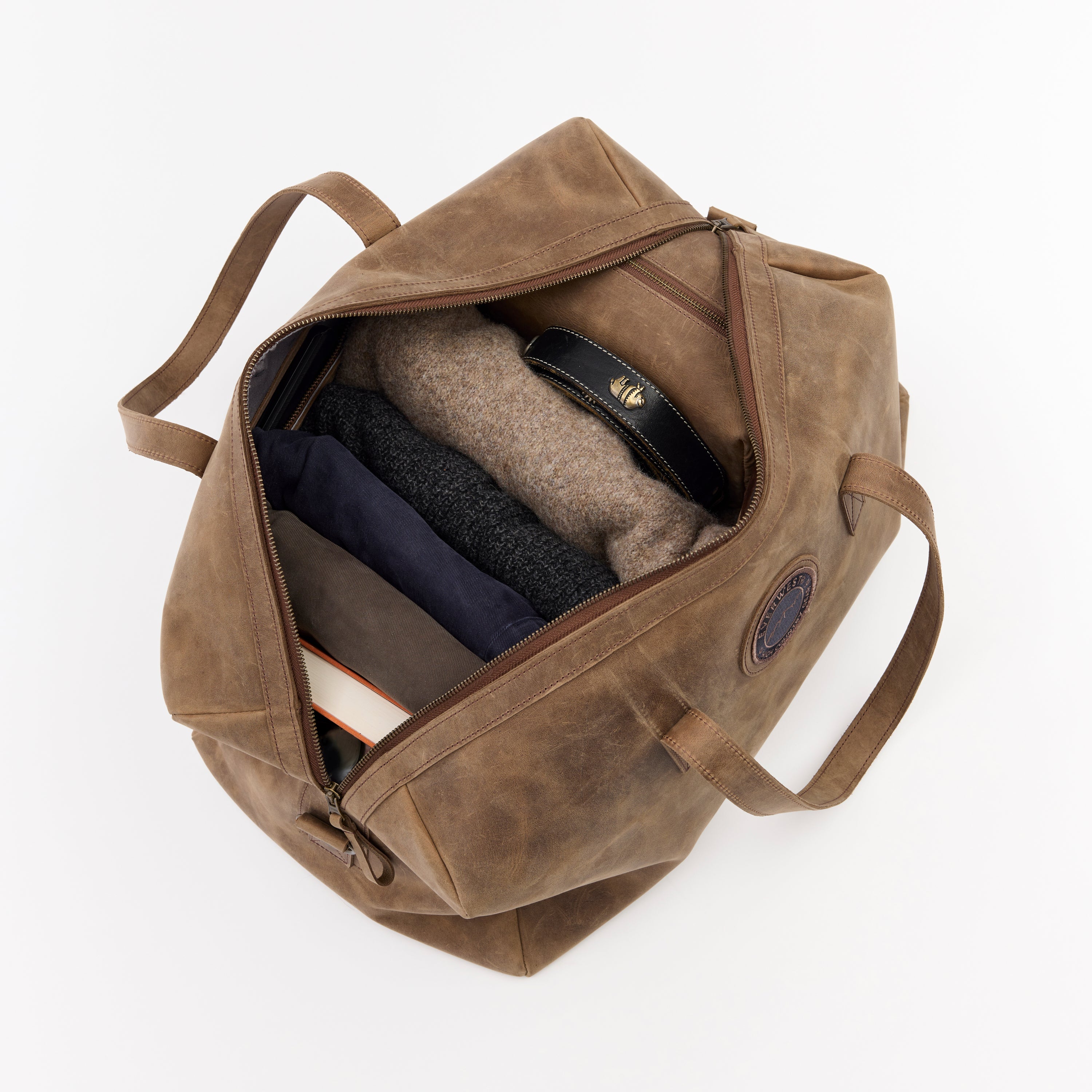 Brown leather duffel bag with items inside on a white background