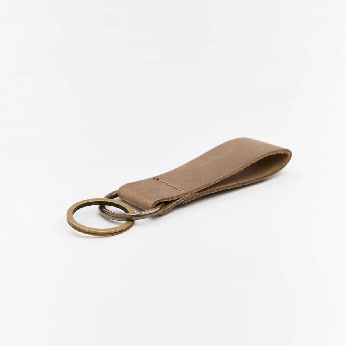 Brown leather keychain with brass ring on a white background