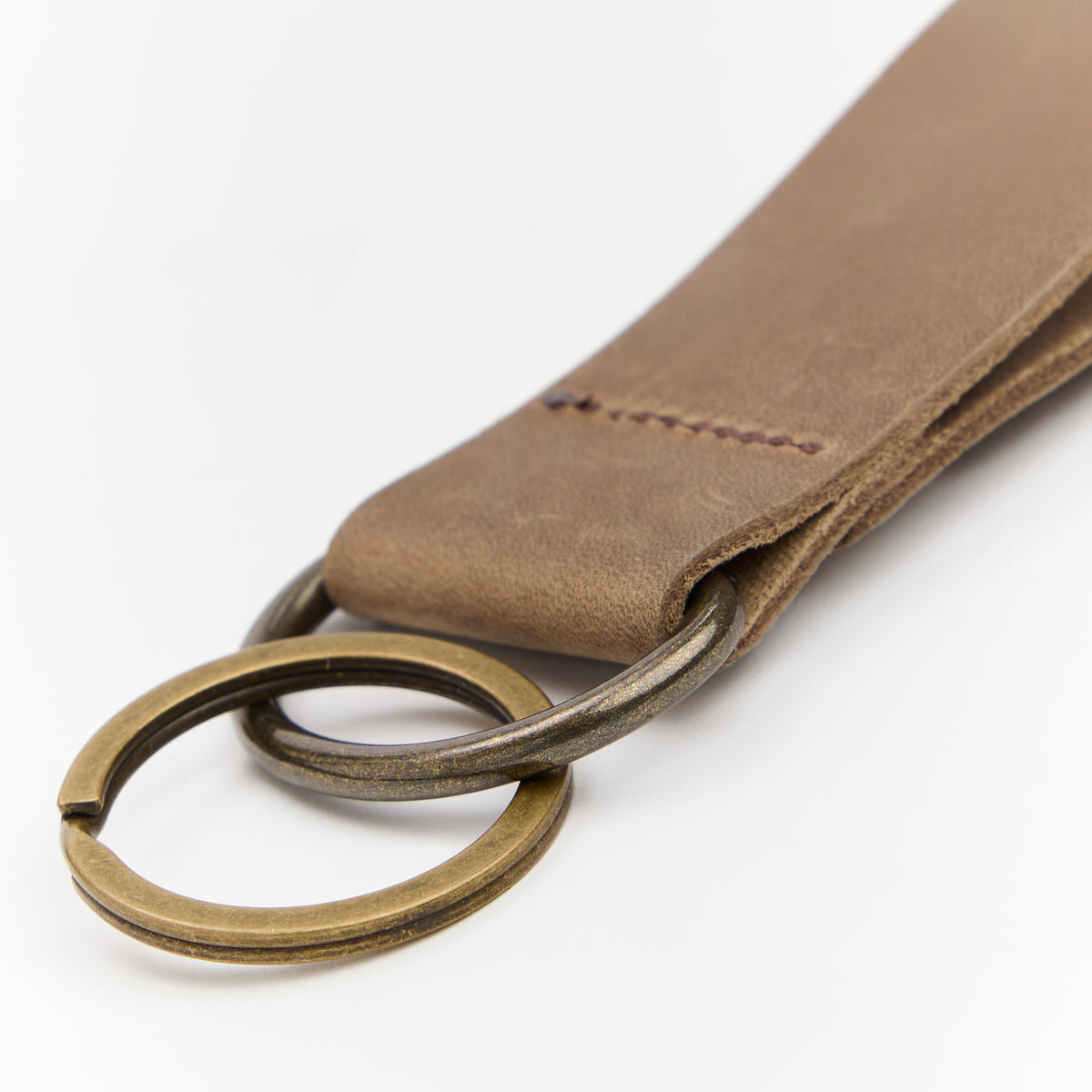 Brown leather keychain with brass ring on a white background