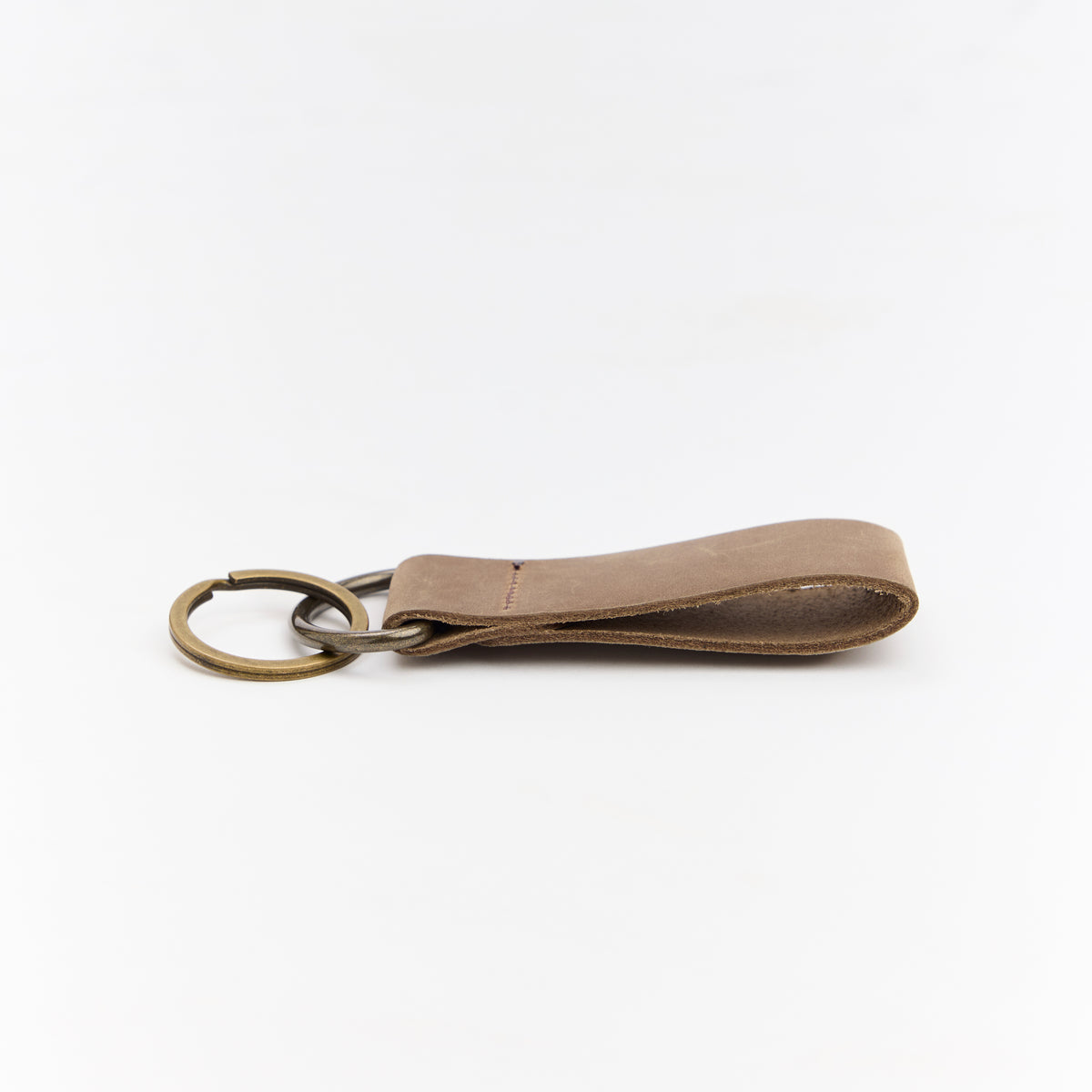 Brown leather keychain with a brass ring on a white background