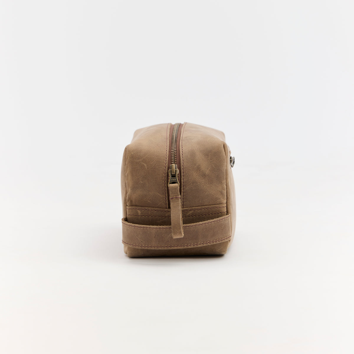 Brown leather toiletry bag with a zipper on a white background