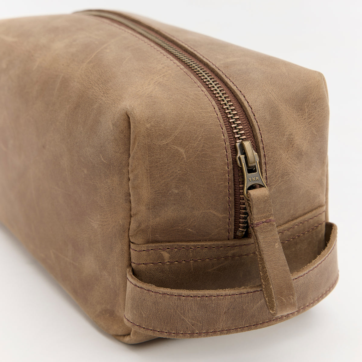 Brown leather toiletry bag with zipper on a white background