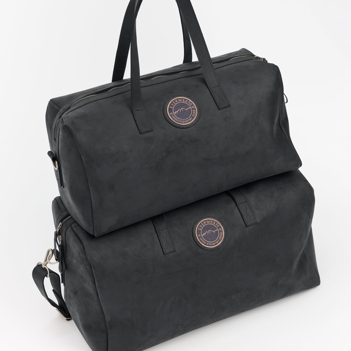 Two different size black leather weekender bags with a brand logo on a white background